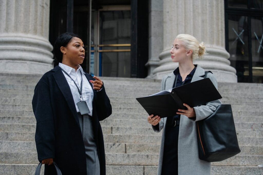 Free Elegant diverse female business partners with documents talking on street Stock Photo