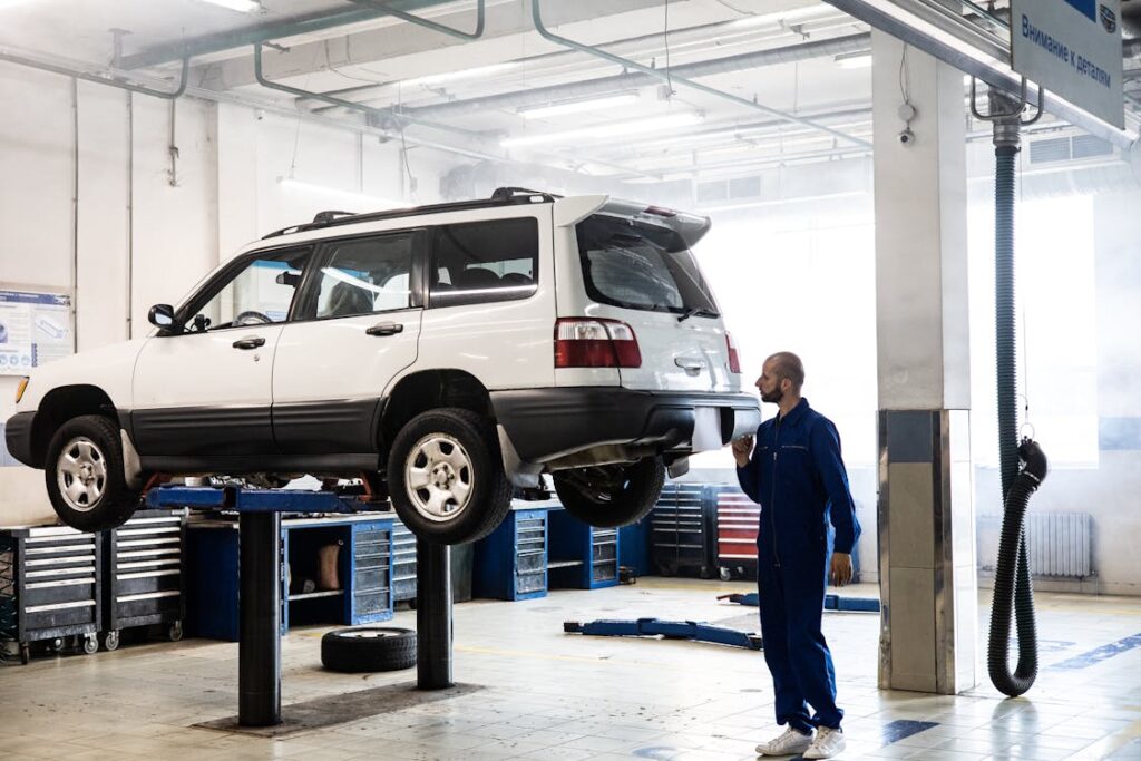 Free Man in Blue Coverall Inspecting A White Car Stock Photo