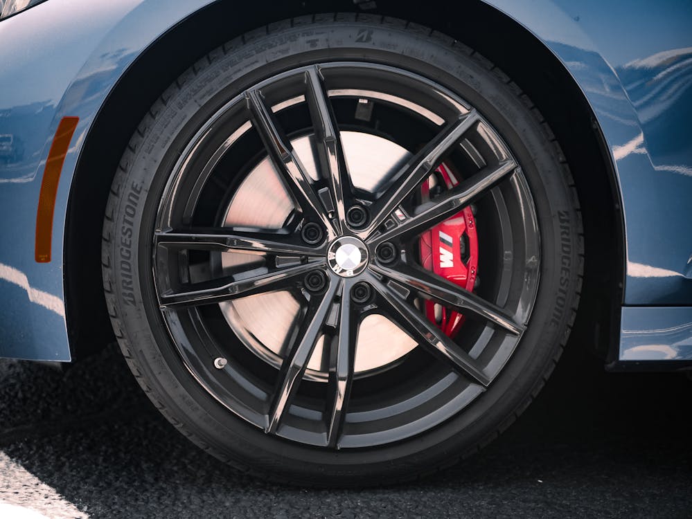 Free The front wheel of a blue car with red brake calipers Stock Photo